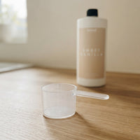 Doseuse La Dose Facile Meraqi Homecare utilisée avec une bouteille de lessive liquide Sweet Vanilla, rituel lessive naturelle